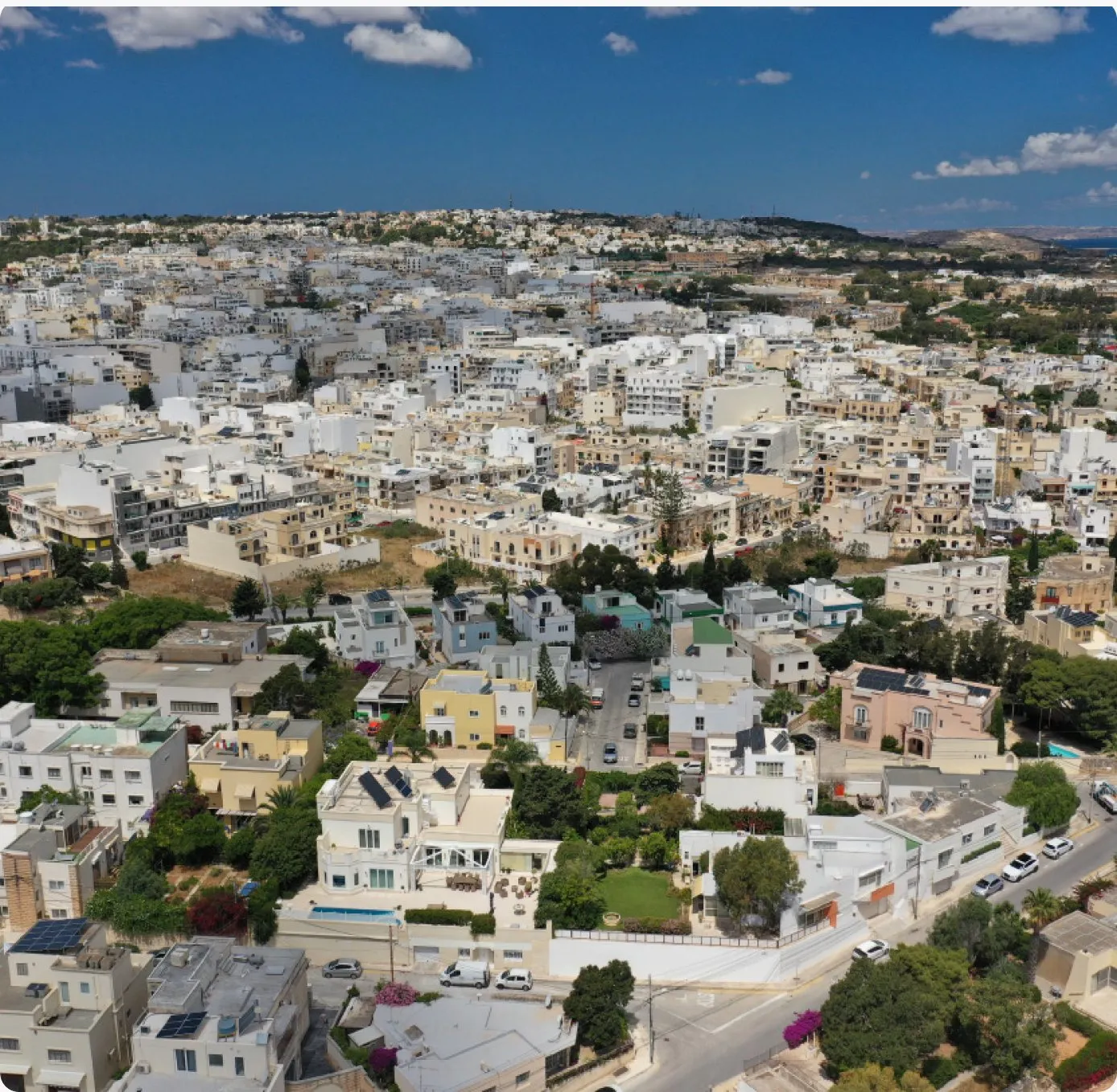 Aerial view of a Maltese town with dense low-rise buildings under a blue sky